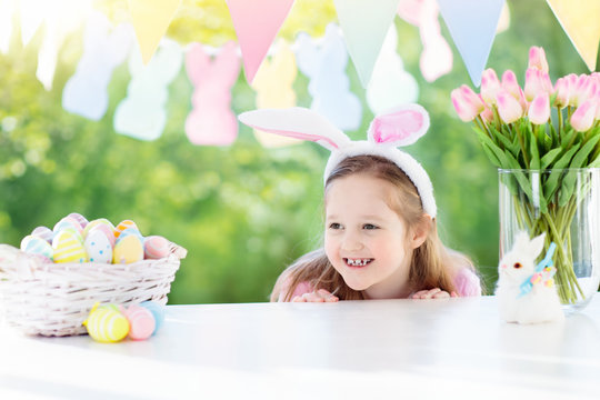 Funny little girl in bunny ears with Easter eggs basket. 