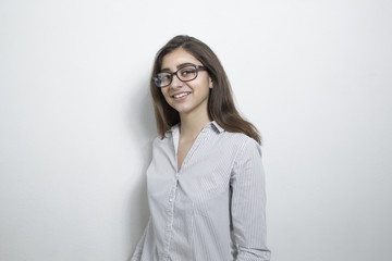 A happy, successful, cheerful indian girl in glasses looks at the camera.