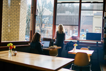 two woman at tables in cafe on computer working