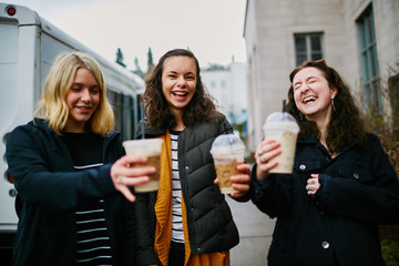 young girls holding cups of coffee drinks while laughing together