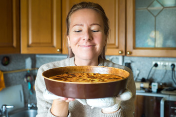 Young woman holding a baking tray with a ready cake