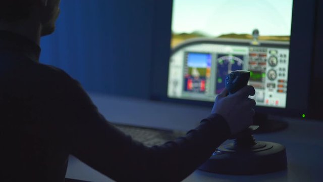 The man playing in computer game with a joystick. evening night time