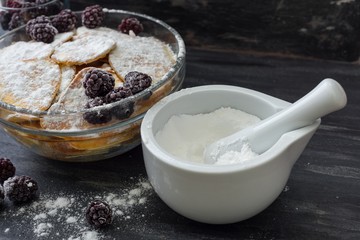 Homemade pancakes with blackberries, powdered sugar. Dark background.