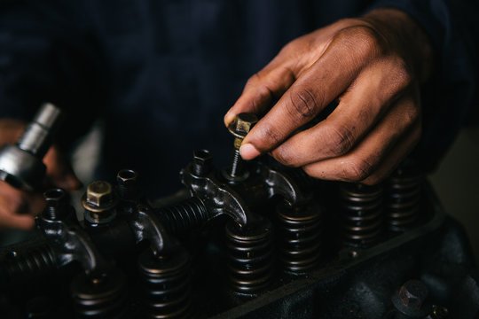 Mechanic fixing an engine for a head gasket repair in a garage.