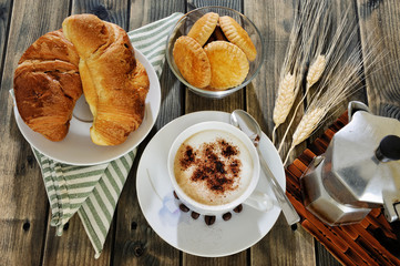 Traditional Italian breakfast with cappuccino and croissants on a rustic wooden table