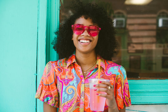 Happy young woman drinking healthy drink outside