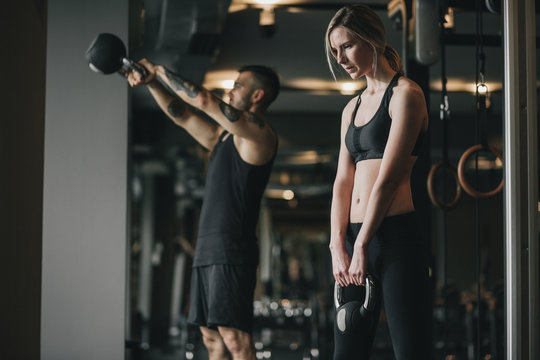 Man and woman exercising with the kettlebell in the gym