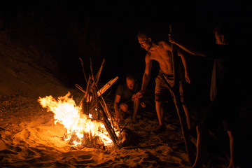Men enjoying near bonfire at the beach during night