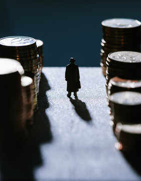 Figurine of businessman standing between stack of coins