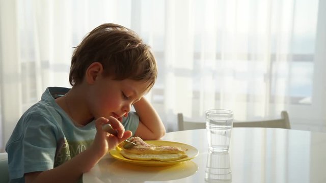 Little child eating omelette in the sunny morning. Healthy nutrition.