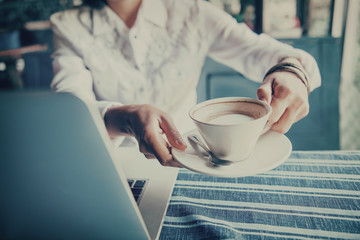 Asian woman  hands holding cup of coffee on  table.Focus on hand