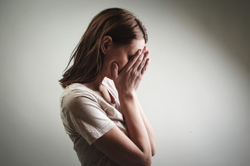 

Portrait of depressed woman, covering face with her hands, side view - obrazy, fototapety, plakaty
