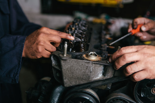 Mechanic fixing an engine for a head gasket repair in a garage.