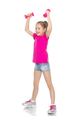 Little girl doing exercises with dumbbells.