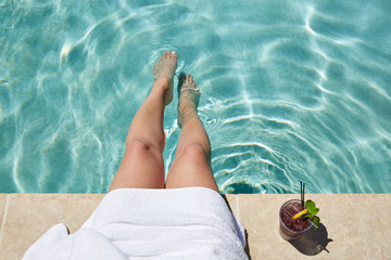 Woman's legs in pool with cocktail on side of the pool
