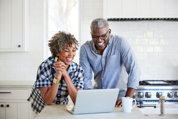 Senior African American couple doing a video chat with family on computer in the kitchen