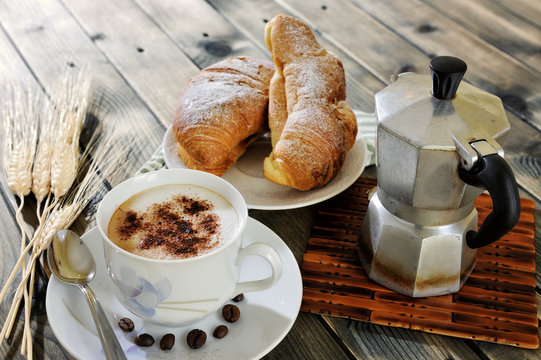Traditional Italian breakfast with cappuccino and croissants on a rustic wooden table