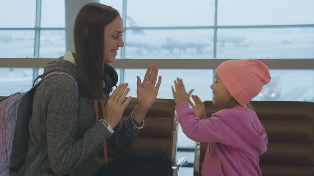 Yound mother and little cute daughter having fun at airport in slow motion.
