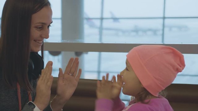 Yound mother and little cute daughter having fun at airport in slow motion.