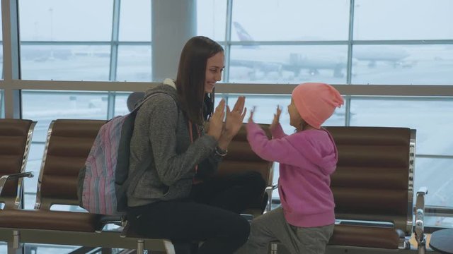 Yound mother and little cute daughter having fun at airport in slow motion.