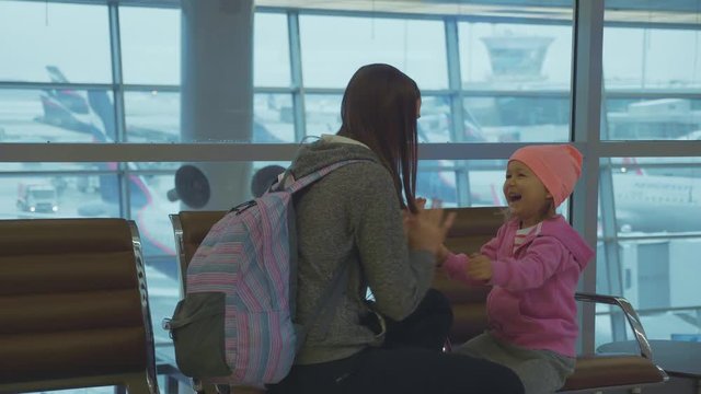 Yound mother and little cute daughter having fun at airport in slow motion.
