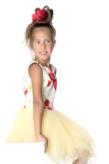 A little girl is looking from behind an empty banner.