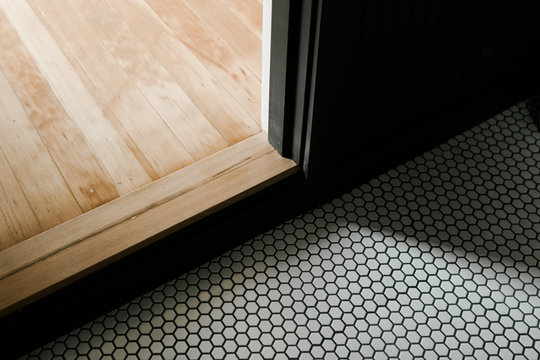 hardwood floor transition to room with white hexagon tile pattern