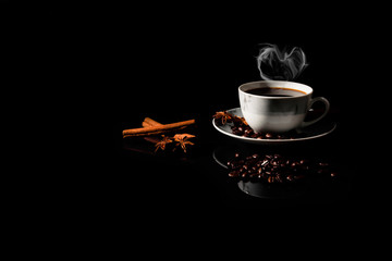 Hot black coffee in a white marble cup with a star aniseed, cinnamon paste reflected on a black...