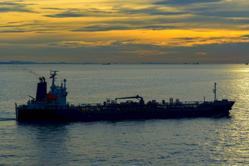 Obraz premium Silhouette of a tanker at sunset in sea.