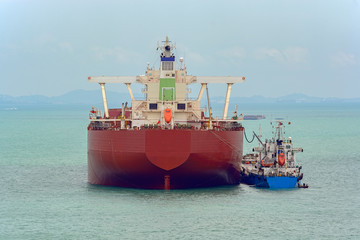 Fototapeta premium Loading anchored oil supertanker via a ship-to-ship oil transfer (STS) from raid tanker