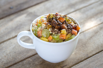 Healthy food, chia seed pudding with mango, green grapes, papaya, oat flakes, coconut milk and muesli, vitamin breakfast in white cup. Morning in Thailand