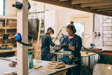 Two Female Carpenters Working in Bright Workshop
