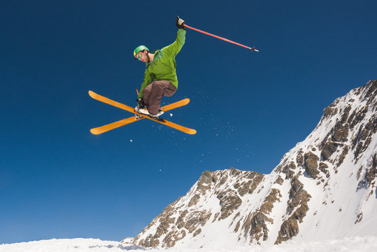 Man performing skiing helicopter trick against the blue sky