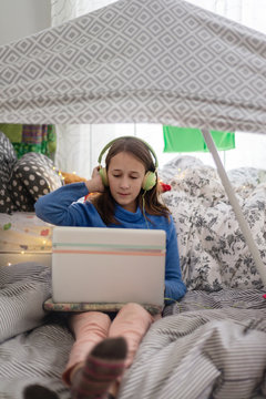 tween girl in her room, under a cubby house, listening to music