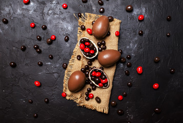 Easter composition with chocolate eggs and sweets, dark background, top view