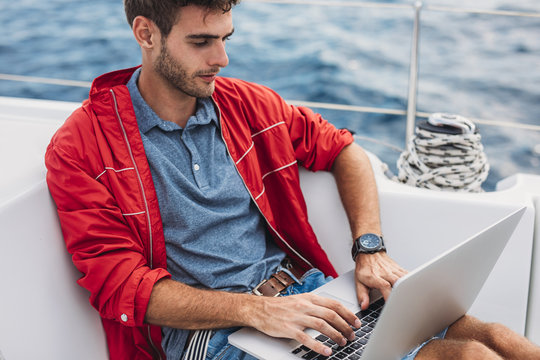 A Man Typing on Laptop on Yacht