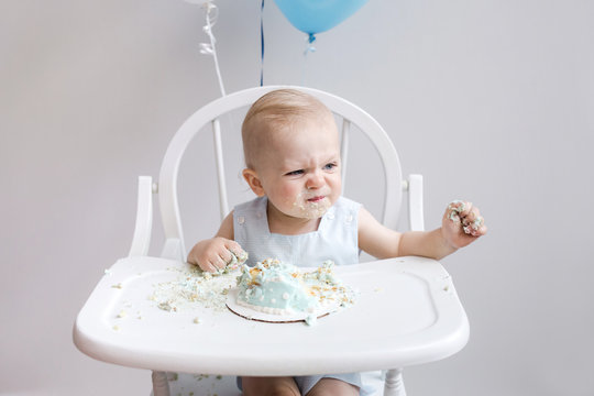 baby making funny face while eating first birthday cake - Powered by Adobe