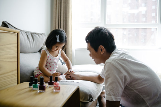 Adorable daughter painting father nails