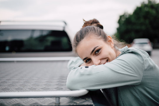 Portrait of beautiful woman smiling leaned on a rare part of car