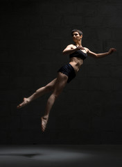 Ballet dancer in top and shorts view in dark room