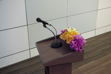 Microphone at the speech podium and flower decoration in seminar or meeting day