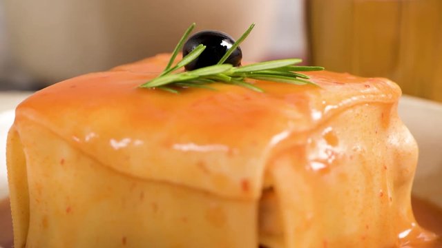 Traditional Portuguese snack food. Francesinha sandwich of bread, cheese, pork, ham, sausages, with tomato beer sauce and French fries. With beer and potatoes. On table.