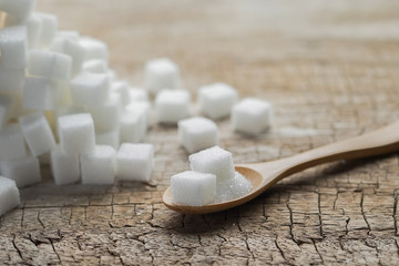 Bowl and scoop with white sand and lump sugar on wooden background