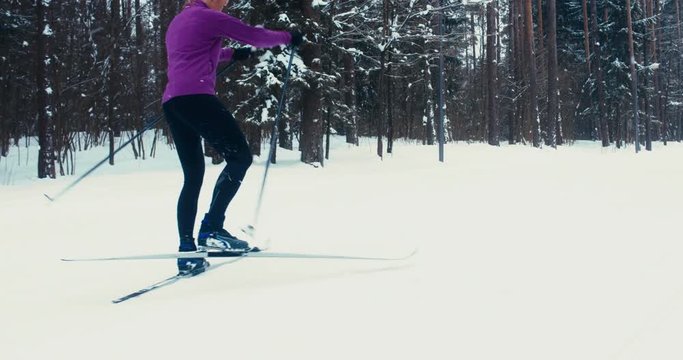 TRACKING Young adult Caucasian female athlete practicing cross-country skiing on a scenic forest trail. 4K UHD 60 FPS SLO MO