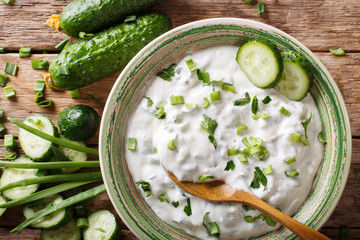 Homemade Indian raita dressing with herbs, spices and cucumber close-up in a bowl. horizontal top view © FomaA