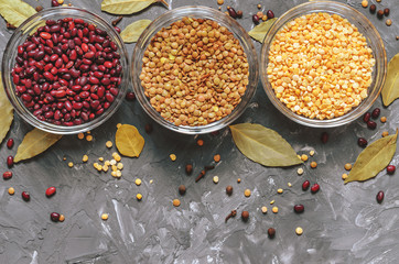 Cereal beans in glass cups: beans, peas and lentils, with spices top view, free space for text