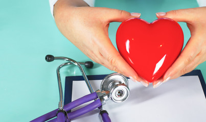 Female doctor with the stethoscope holding heart