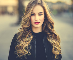 Young blonde girl with beautiful blue eyes wearing black jacket.