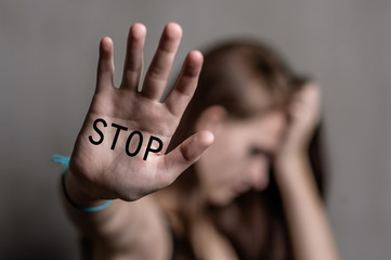 Sad teenage girl shows the inscription "stop" on the palm