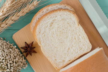 Sliced soft and sticky delicious white bread on wood cutting board prepare for breakfast on blue wooden table in top view flat lay to present bread texture or pattern. Homemade bakery concept.